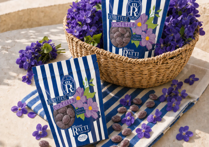 Sachets d'olivettes violette Maison Ratti dans un panier d'osier, entourés de violettes fraîches